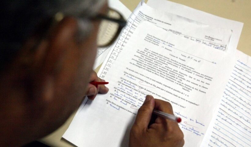Professor corrigindo prova em casa. Câmara de Taubaté deve votar projeto que cita adequação da jornada de professores
